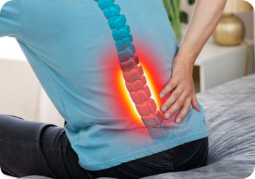 A man is bending forward and holding his lower back. An image of a spine with a red painful area in the lumbar region is superimposed on his back. 